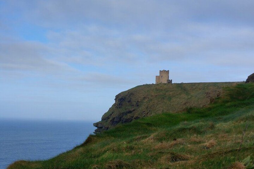 Ett kustlandskap med ett slott på en grönskande kulle med utsikt över havet. 2