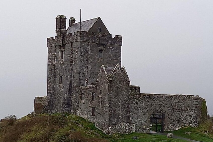 Un vaste château historique en pierre, doté d’une tour imposante, qui se dresse sur une colline verdoyante. 3