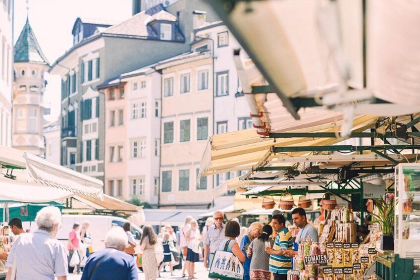 A busy outdoor market with people shopping and vendors selling goods. 3