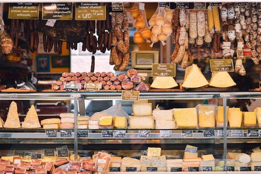 A variety of cheeses and cured meats on display in a shop. 2