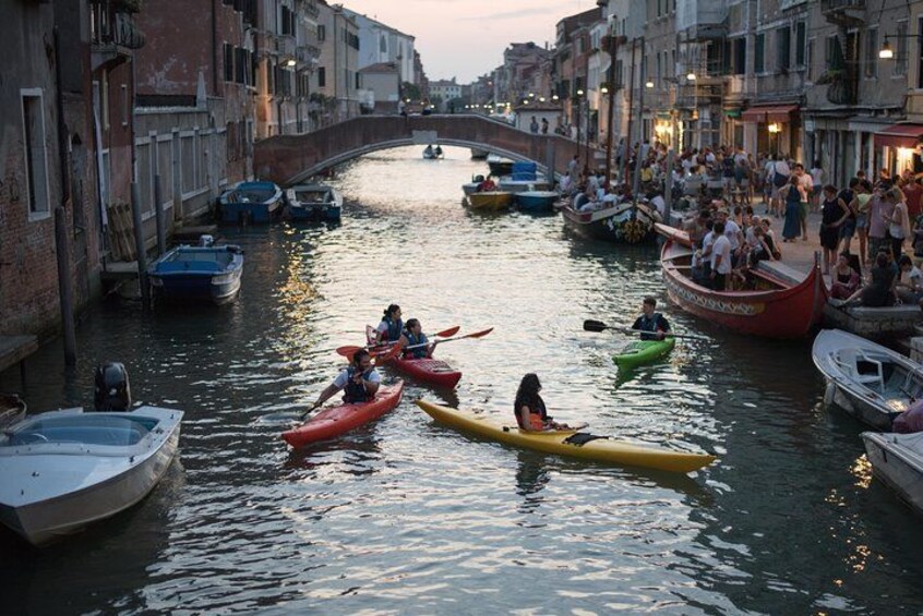 A canal with boats, people on foot, and a bridge in the background. 4