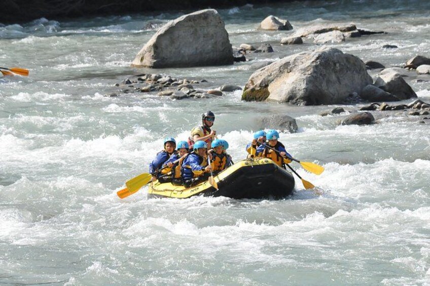 Un groupe de personnes à bord d’un radeau navigue sur une rivière à courant rapide, entourée de rochers. 5