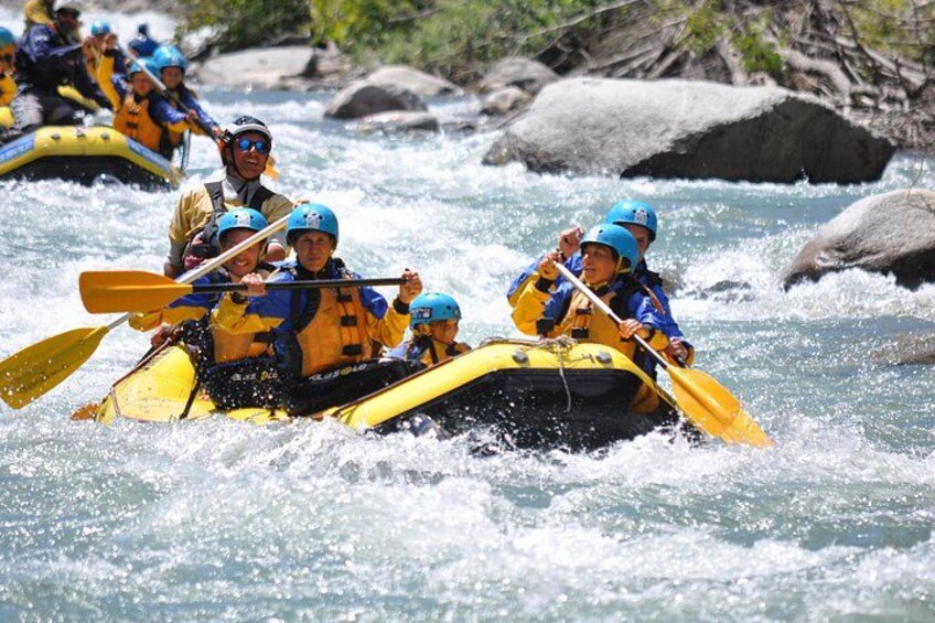 Un groupe de personnes à bord d’un radeau jaune navigue sur une rivière à courant rapide. 3
