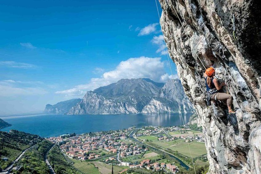 Eine Person klettert an einer Klippe mit herrlicher Aussicht auf einen See und eine Stadt darunter. 1
