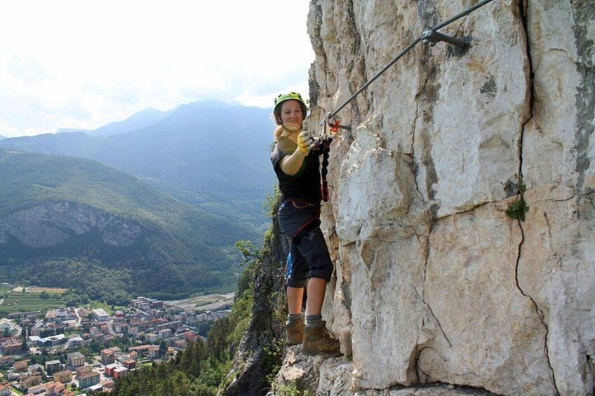 A person rock climbing on a cliff with a town and mountains in the background. 2