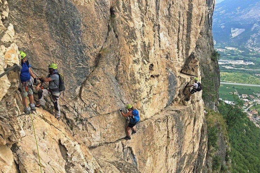 A group of climbers on a steep rock face with a valley in the background. 4