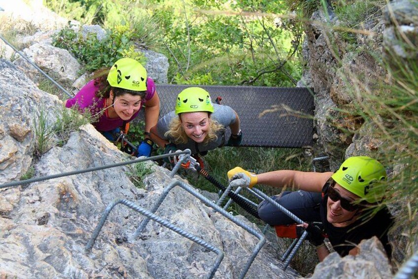 People climbing a rocky slope with metal ladders. 3