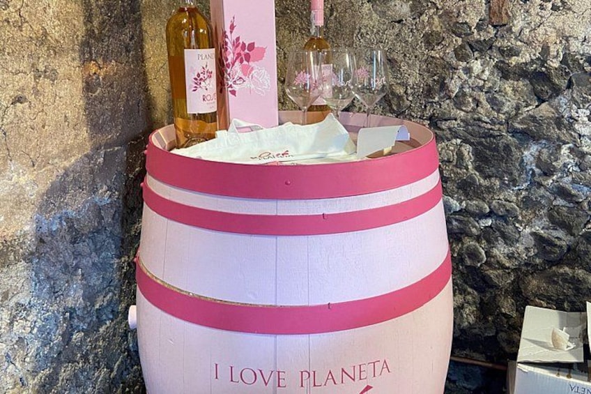 En lyserød tønde med teksten 'I LOVE PLANETA' påtrykt, fyldt med vinflasker og glas. 3