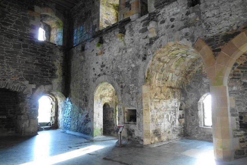 An interior of a historic stone building with arched doorways and a high ceiling. 5