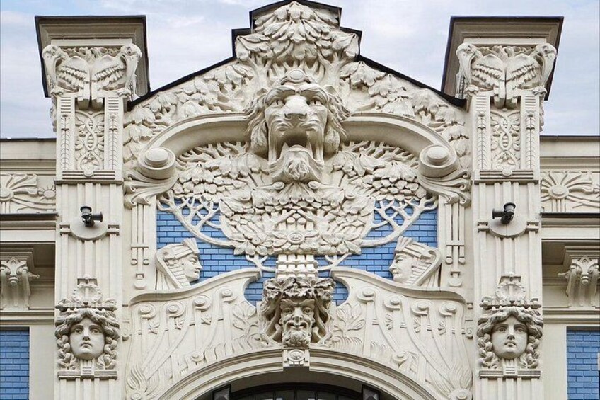 An ornate building facade with intricate carvings and a blue-tiled section. 1