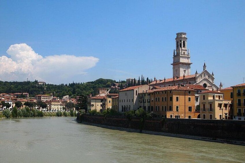 A river with buildings along the banks, a prominent tower, and a hilly landscape in the background. 4