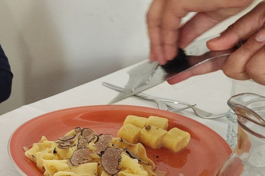 A person cutting truffles on a plate of pasta. 2