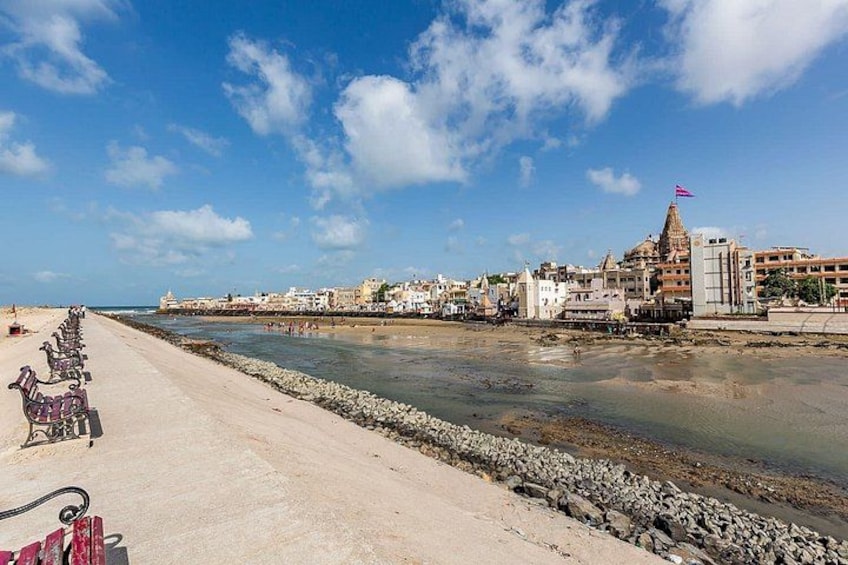 A coastal cityscape with a sandy beach, a river, and a prominent temple with a flag. 1