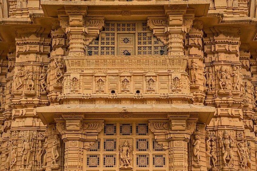 A detailed sandstone temple facade with intricate carvings and multiple small windows. 3