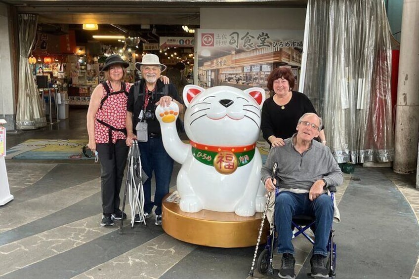 A group of people standing in front of a large cat statue. 5