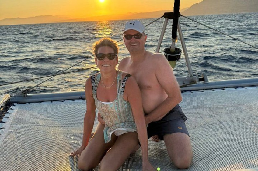 Deux personnes sur un bateau, avec un coucher de soleil en arrière-plan. 2
