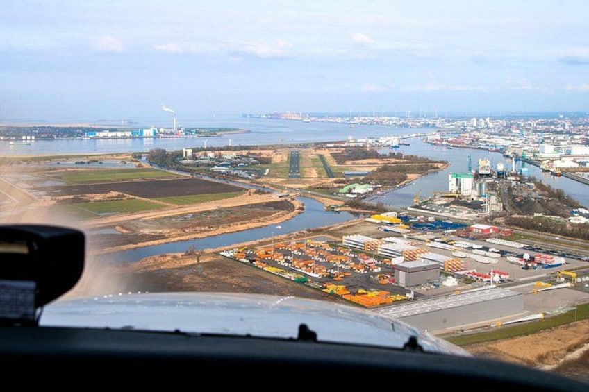 Ett flygbildsbild av ett industriområde med en flod, byggnader och en bro. 1