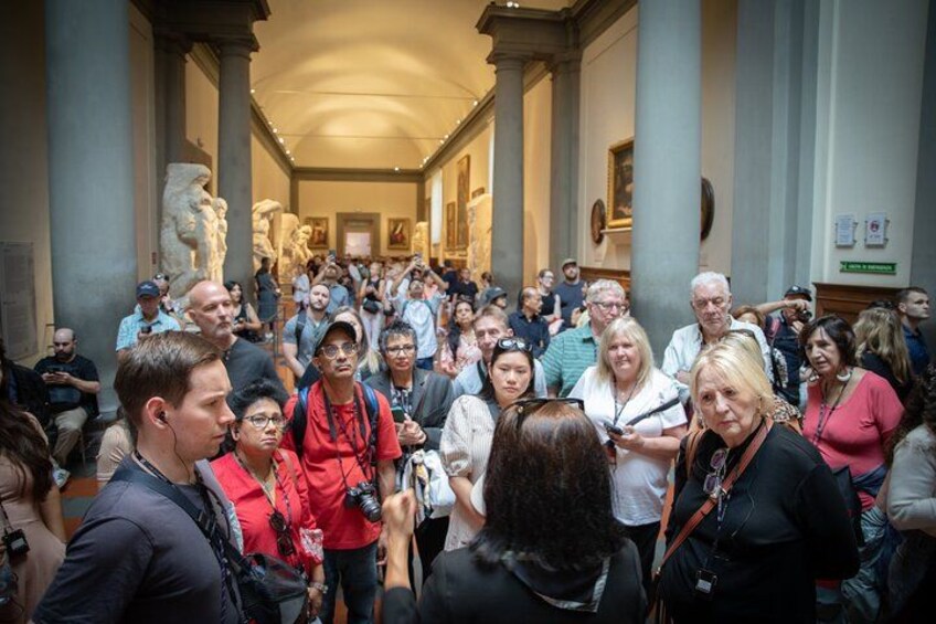 A crowded museum corridor with visitors and staff. 2