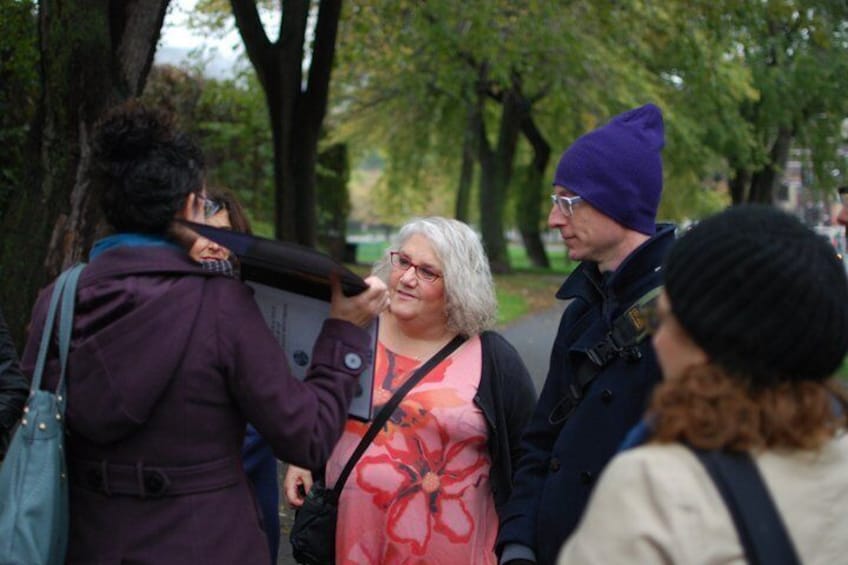 En grupp människor i en park med träd, och en person som håller i en kamera. 1