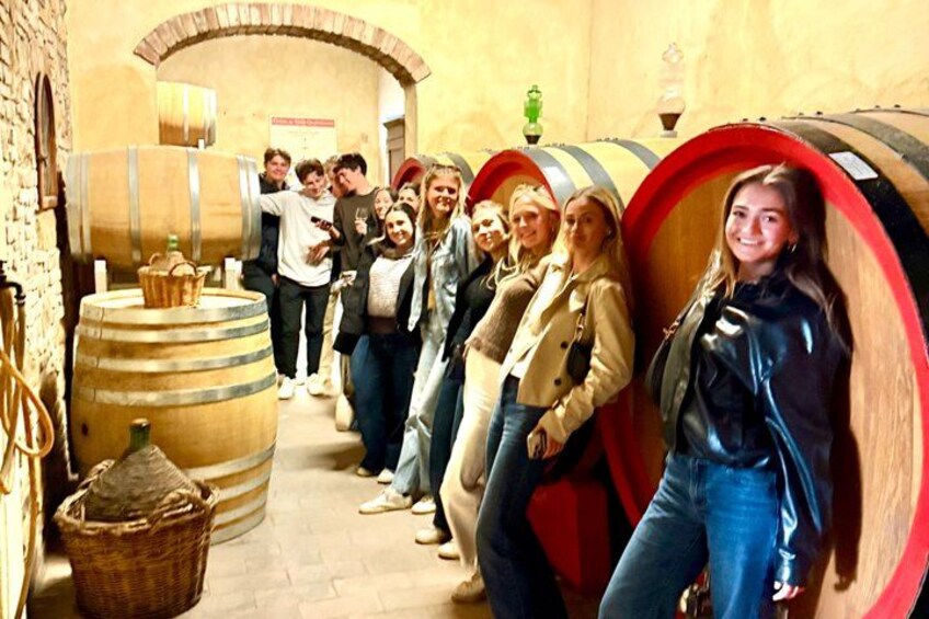 Un grupo de personas en una bodega de vino con barriles de madera grandes. 2