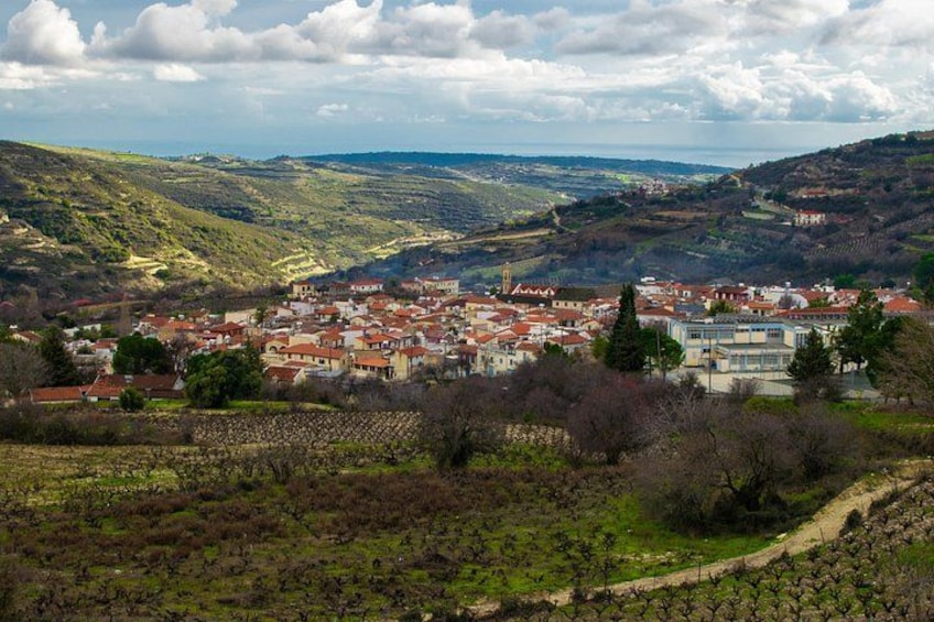 A town nestled in a valley with vineyards, a prominent church, and rolling hills in the background. 1