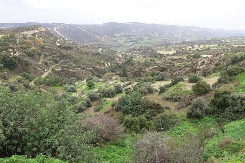 A hilly landscape with dense vegetation, a winding road, and distant hills. 2