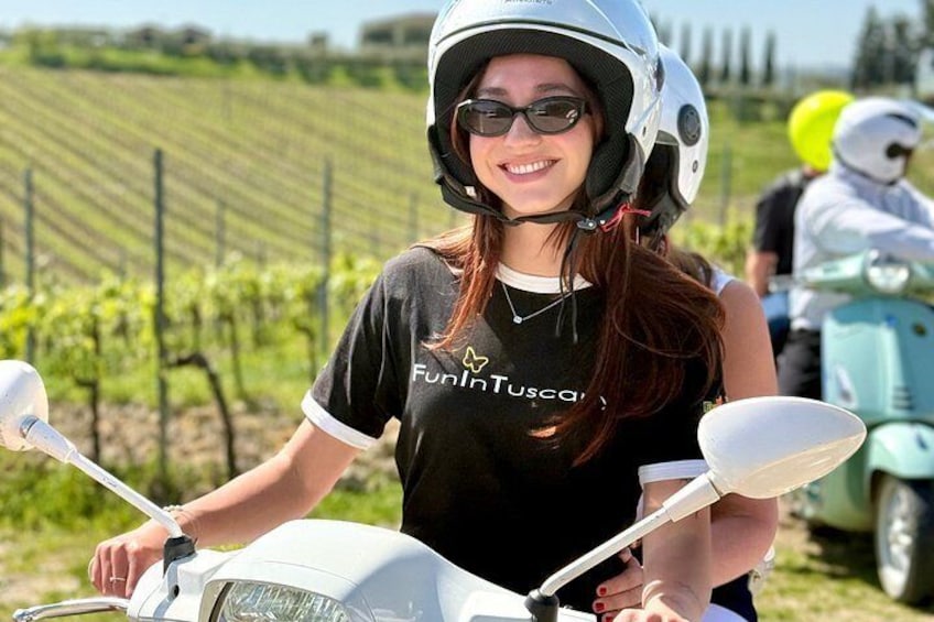 A person on a white scooter in a vineyard. 1