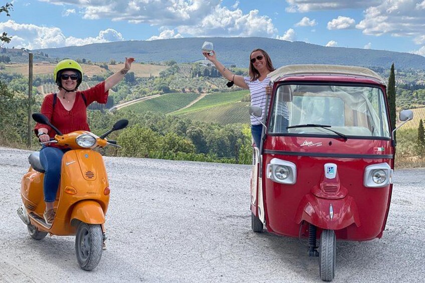 A person on a yellow scooter and a red three-wheeled vehicle on a gravel path with a scenic landscape in the background. 4