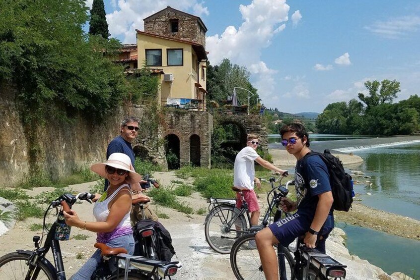Un grupo de personas en bicicletas cerca de un río, con un edificio al fondo. 3