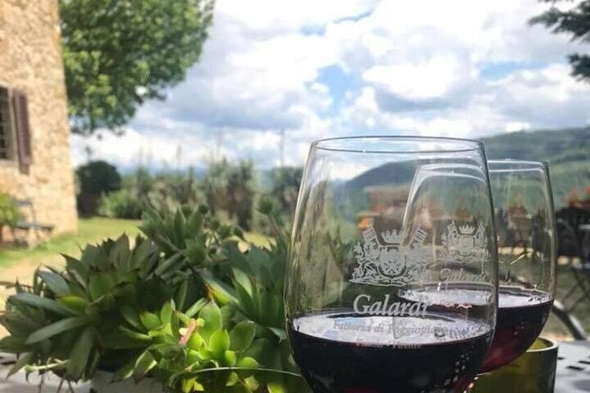 Two wine glasses with embossed text, a stone building, and lush greenery in the background. 2