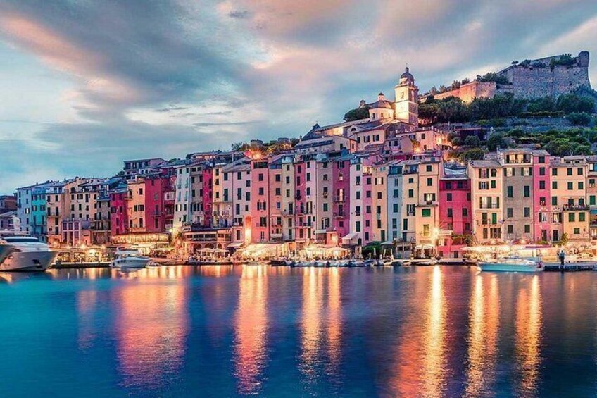 A coastal town with colorful buildings, a castle on a hill, and boats in the water. 4