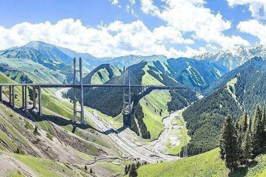 A bridge over a valley with mountains in the background. 4
