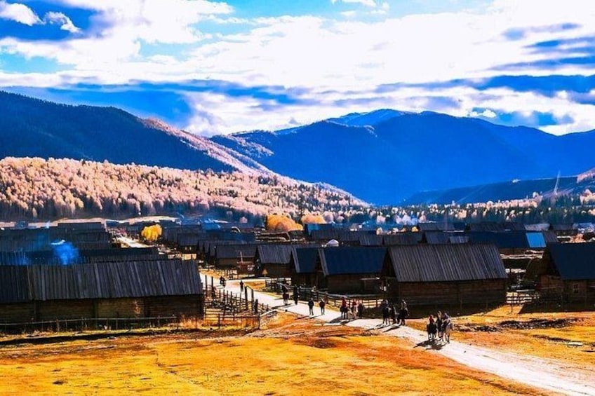 A village with wooden houses, a dirt road, and mountains in the background. 3