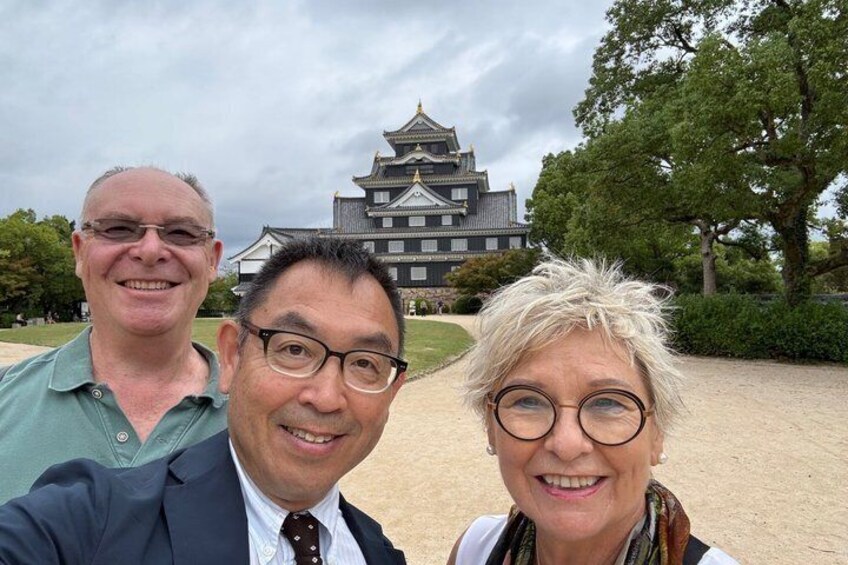 Three people in front of a traditional Japanese castle. 1
