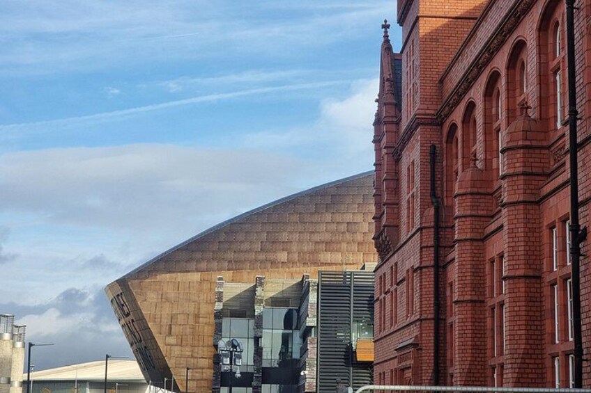 A modern building with a curved roof, adjacent to a traditional red brick building. 3