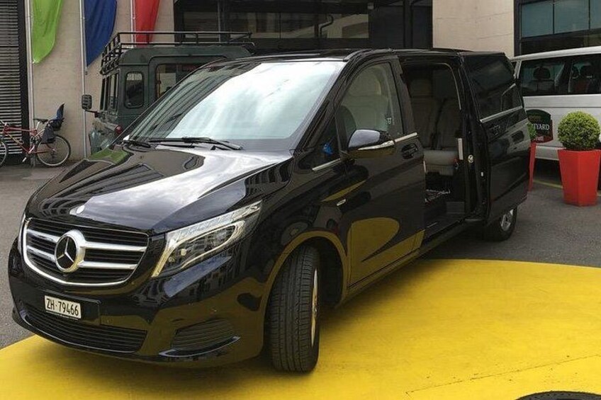 A black Mercedes-Benz SUV parked on a yellow surface with a building and a bicycle in the background. 1
