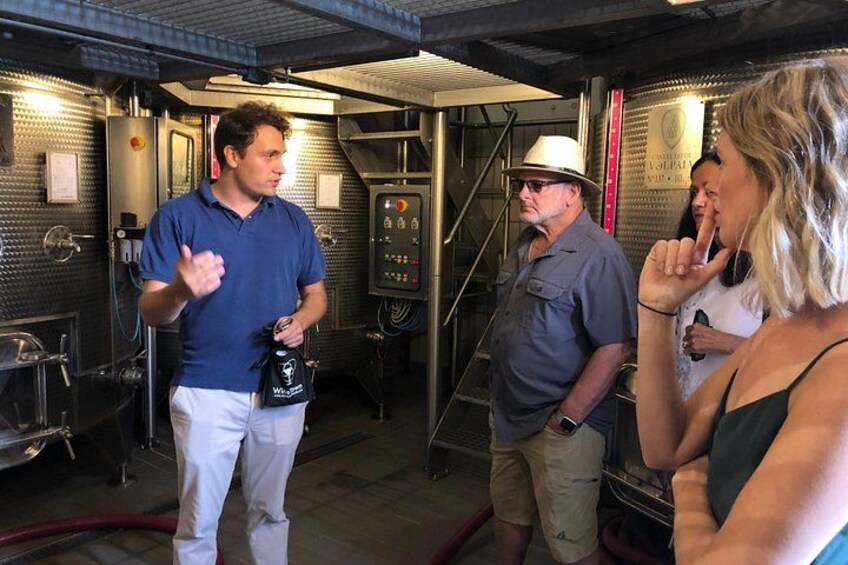 Un groupe de personnes se trouve dans un bâtiment technique, où l’on peut voir des machines et des panneaux de contrôle. 3