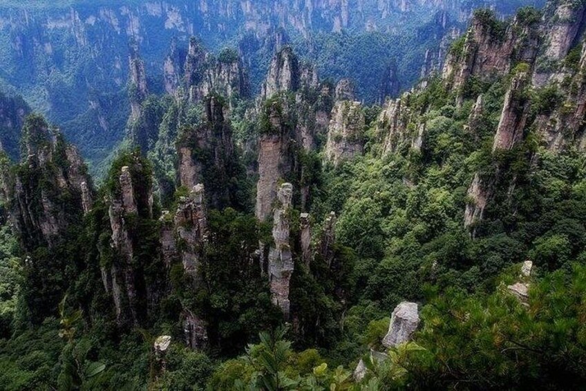 A mountainous landscape with tall, narrow rock formations and dense green vegetation. 2
