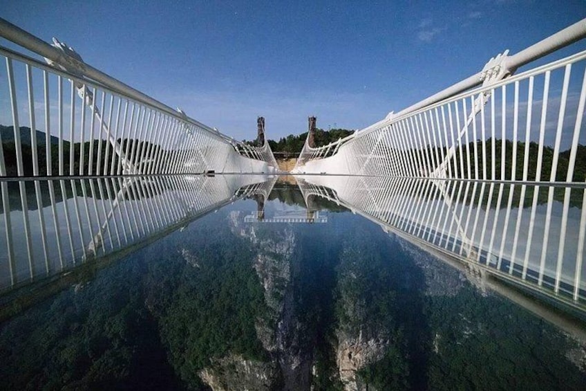 A bridge with a clear reflection in the water, a distant mountain, and a clear sky. 5