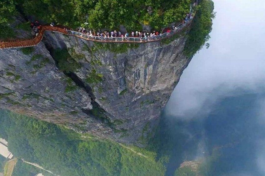 A suspension bridge with people walking across a steep cliff. 3