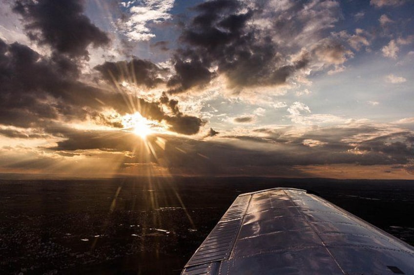 An airplane wing, a cloudy sky, and the sun setting or rising. 4