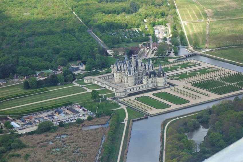A large castle with a moat, surrounded by lush greenery and a river. 2