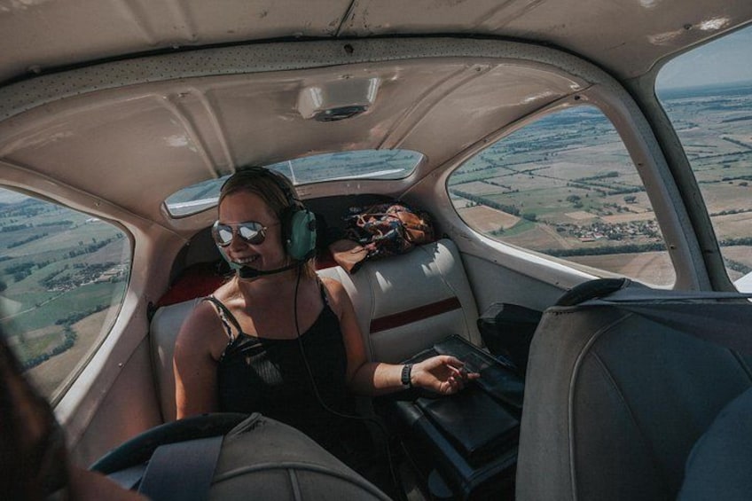 A person in a cockpit with a view of farmland through the window. 3