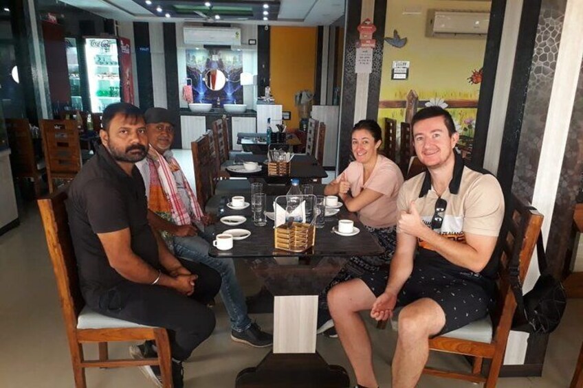 Four people seated at a table in a restaurant with a menu, glasses, and a coffee machine in the background. 2