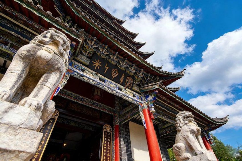 Un edificio tradicional chino con arquitectura ornamentada, que incluye pilares rojos y estatuas de leones de piedra en la entrada. 5