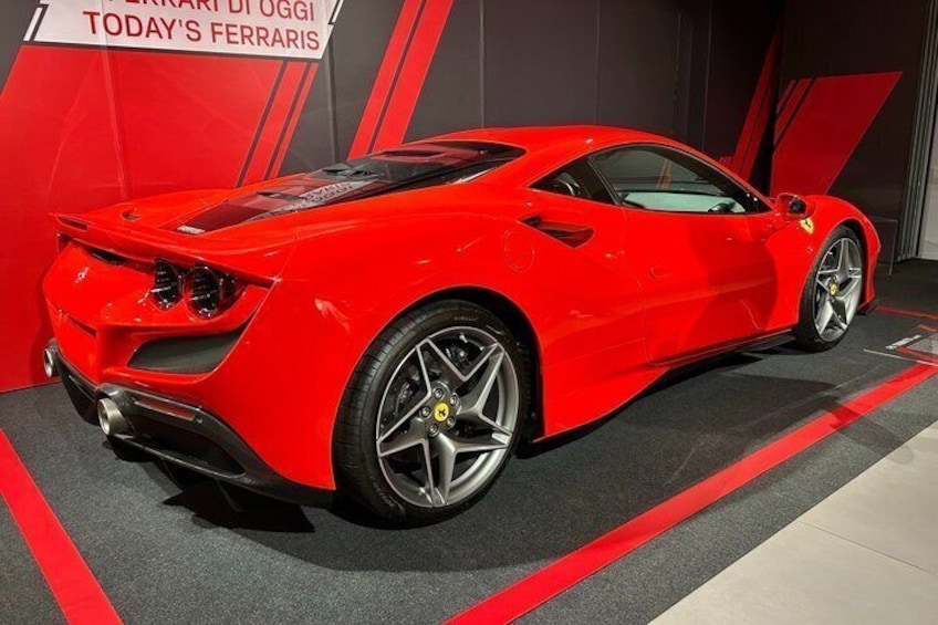 Un auto deportivo rojo con un diseño aerodinámico, ruedas grandes y un spoiler trasero llamativo. 4