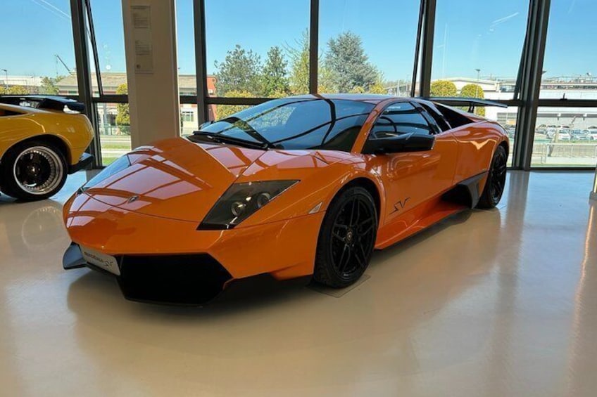 Een feloranje sportauto in een gebouw met grote ramen. 4