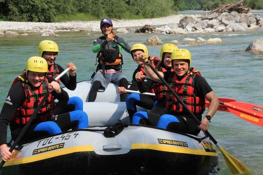 A group of people in a raft on a river, wearing helmets and life jackets. 5