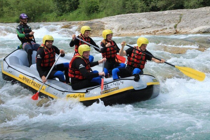 A group of people in a white inflatable raft with yellow and black markings, paddling on a river. 4