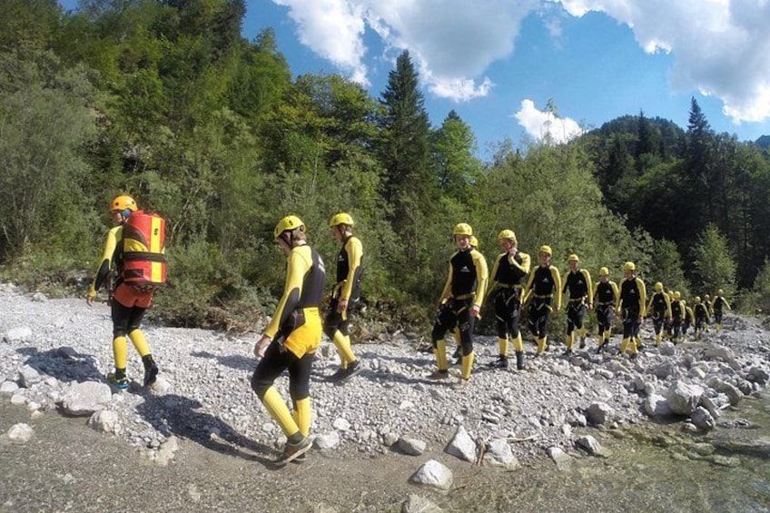 A group of people in yellow and black uniforms walking on a rocky path surrounded by trees. 3